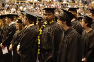 waiting graduates in cap and gowns - African American student facing camera