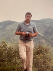Charles with a camera and mountains in the background