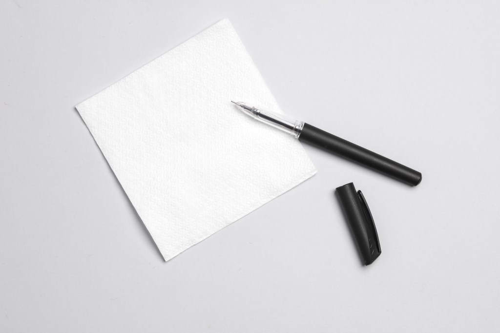 White empty napkin and pen on gray background